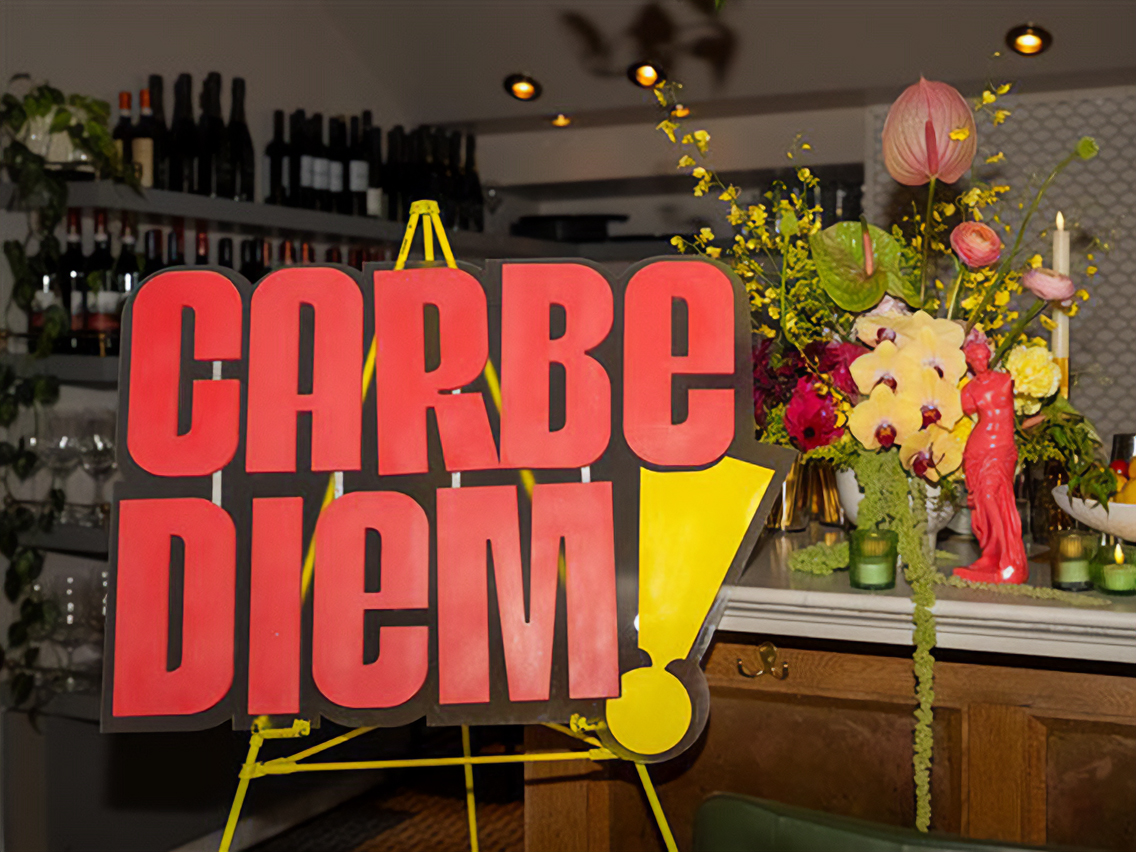 A sign with the Carbe Diem logo sits in a restaurant