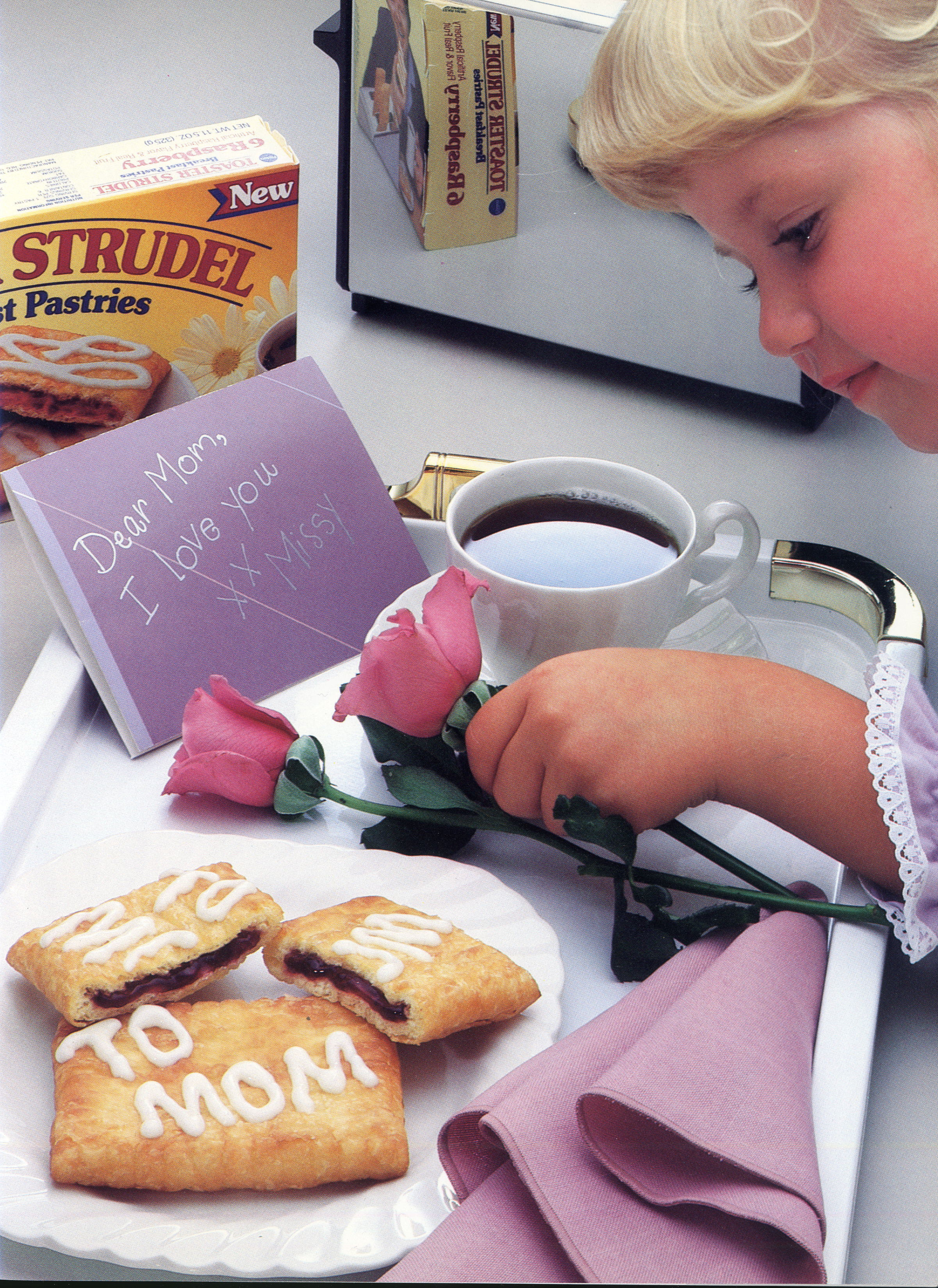 Girl making breakfast tray for Mother's Day with "To Mom" written on the Toaster Strudel with icing